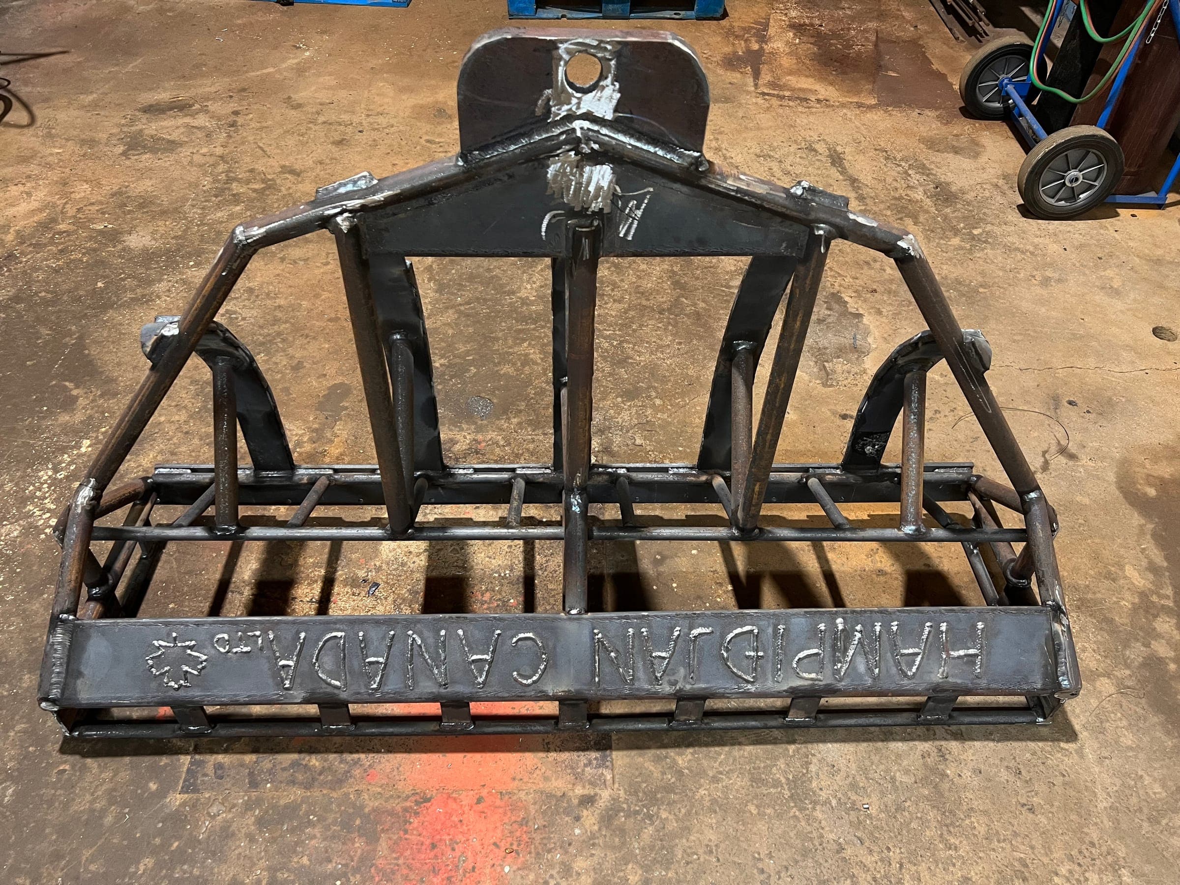 A five-bar sea cucumber dredge frame in bare welded steel on the shop floor