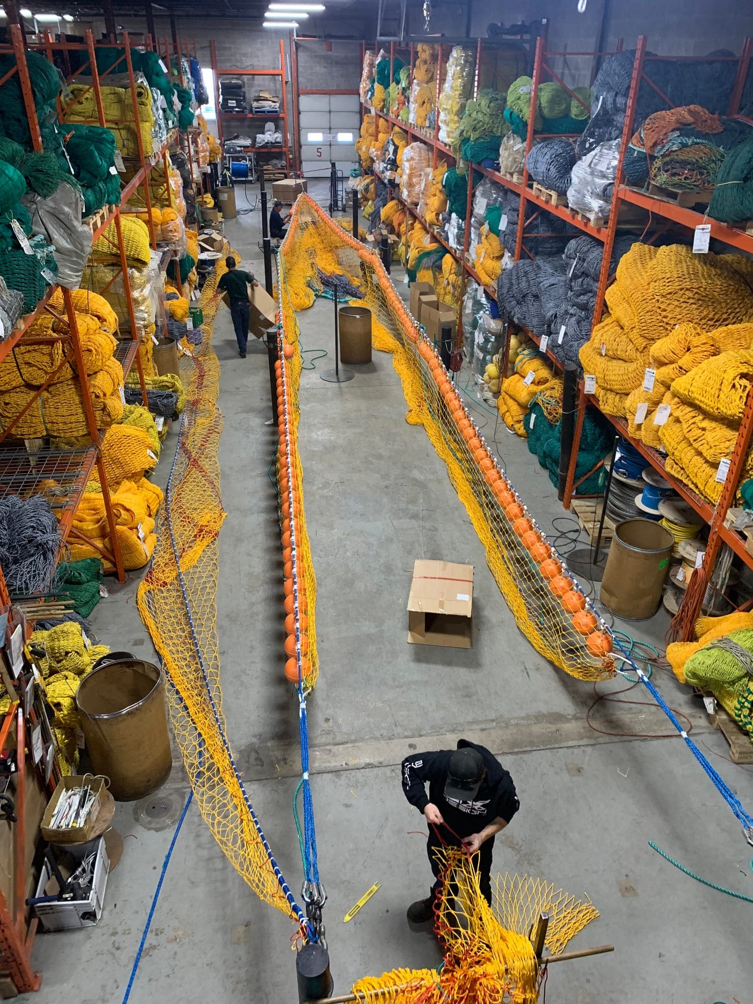 A trawl laid out down the aisle of our net loft, a crew member hanging netting to the headline.