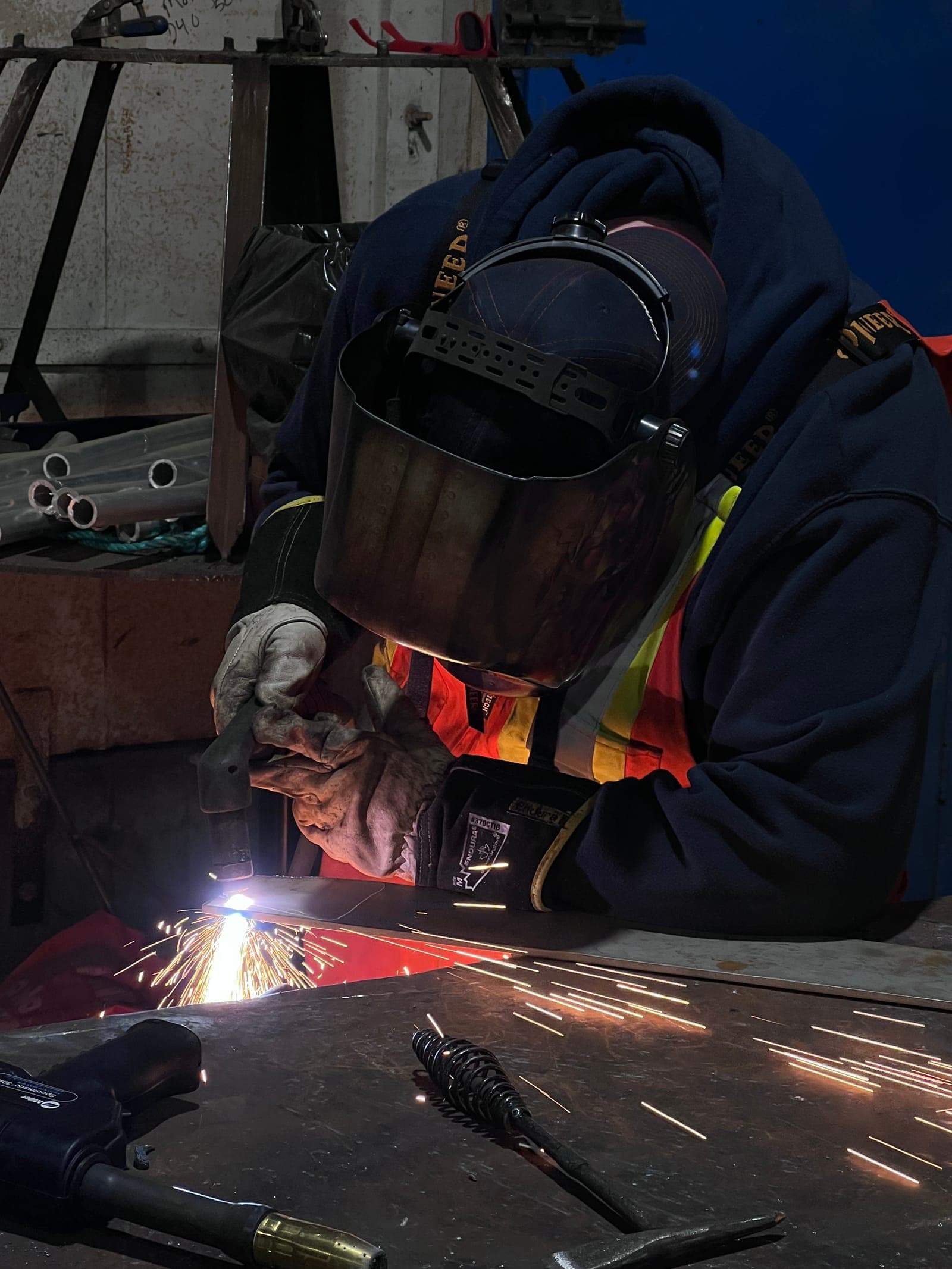 A welder at the bench with the hood down and the arc struck
